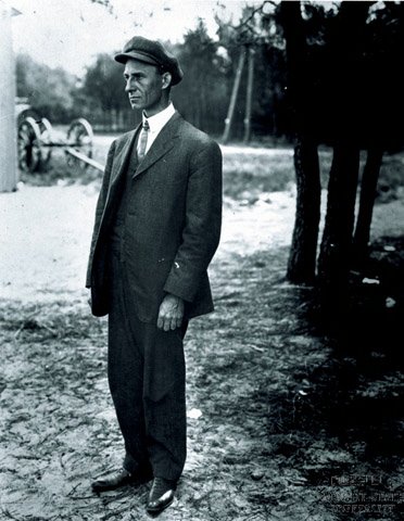 Wilbur Wright wearing his famous cap, standing, facing to his right at Le Mans, France
