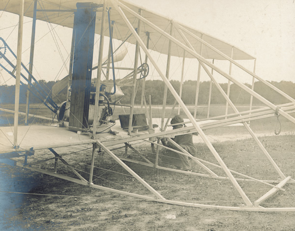 Mechanic Charles E. "Charlie" Taylor making adjustments to the controls of the Wright Model A Flyer, 1908. (photo ms1_39_45)