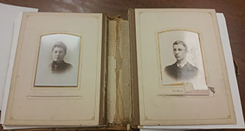 Wright Family Album open to page of Katharine (sister) and Wilbur Wright as teenagers. Board pages shown completely detached from spine. Split window housings in boards torn and creased on some pages.