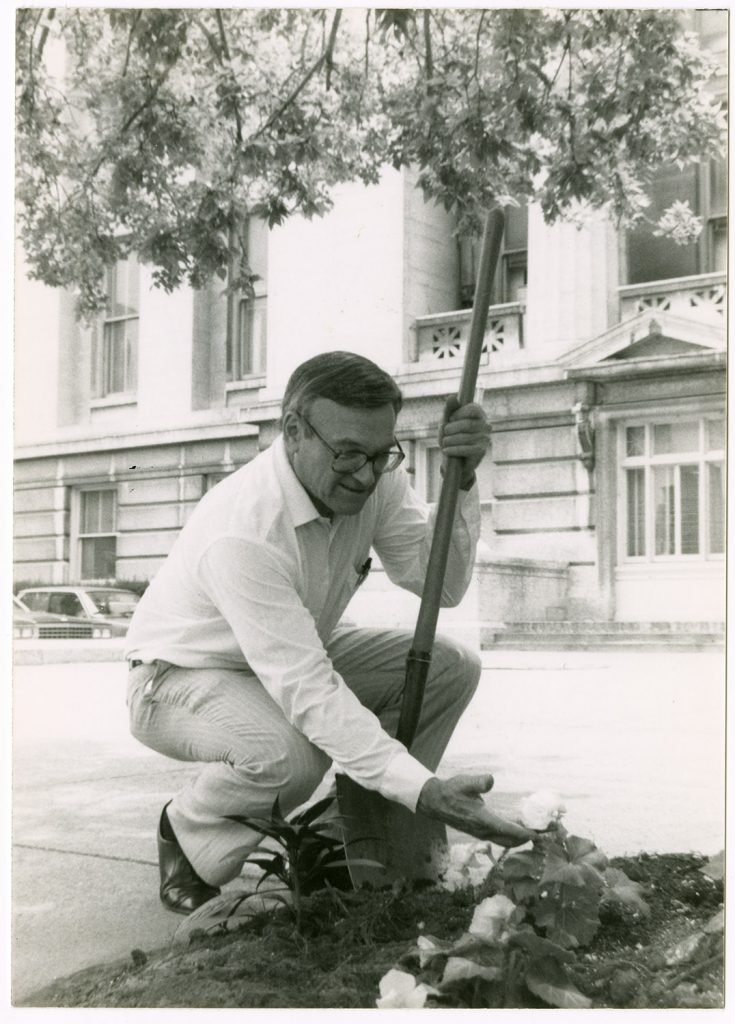 A photograph of senator Charles Horn planting marigolds outside of the Ohio State House. Horn was involved in beautification projects, particularly the planting of marigolds, throughout his political career. Circa 1984-2001. (ms629_018_001_001)