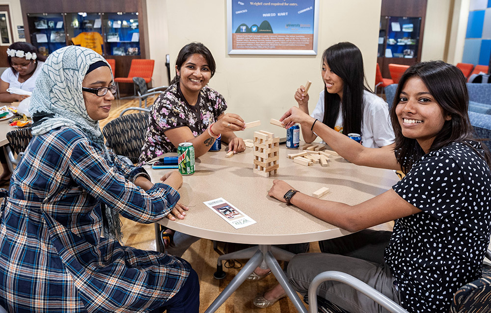 four women play games and smile in library group study room